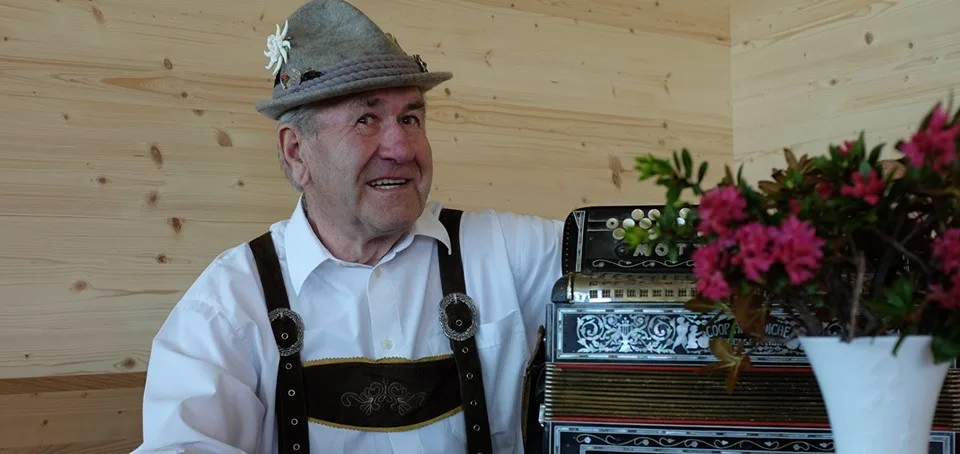 Seniorchef Elmar Simma in Tracht neben seinem Akkordeon