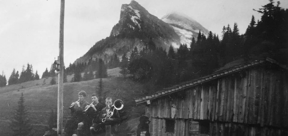 Historische Schwarzweißaufnahme: die alte Alphütte aus Holz, dahinter die Kanisfluh