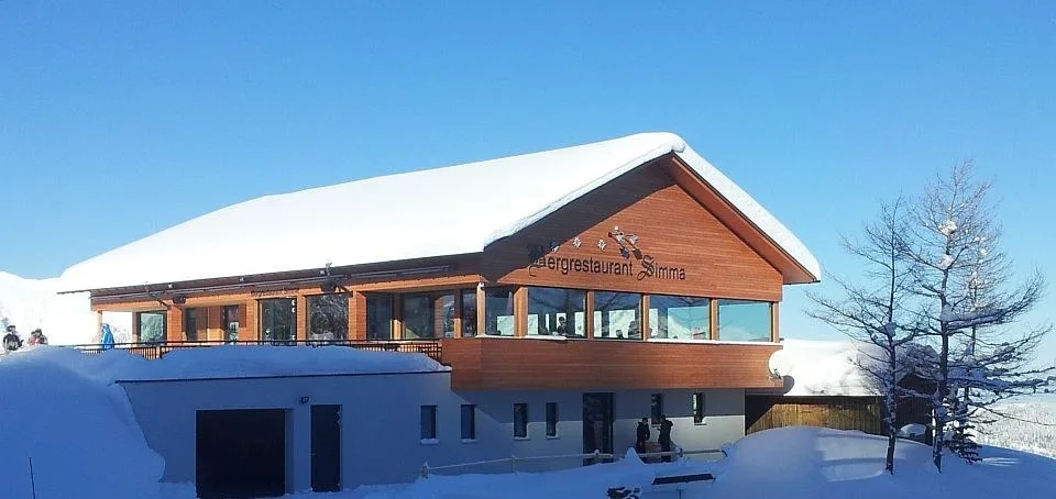 Das tief verschneite Haus im Winter mit dem Schriftzug über der Fensterfront