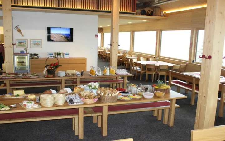 Gedeckte Frühstückstafel im Gastraum mit Gebäck, Müsli und Geschirr